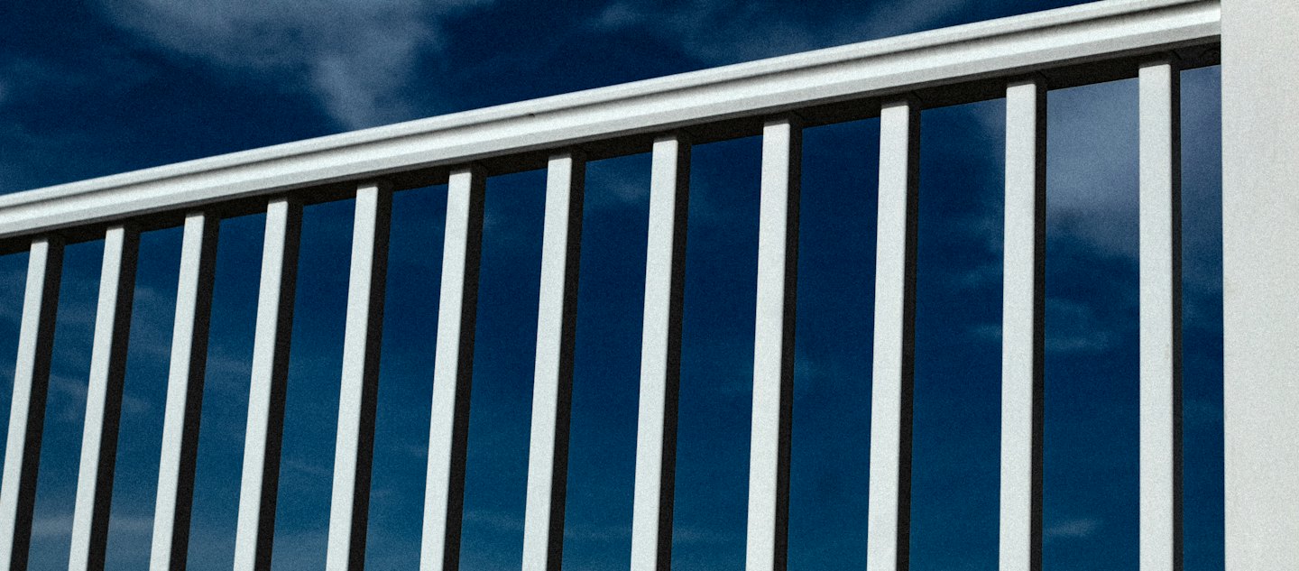 Vit arkitektonisk räcke mot en klarblå himmel.